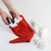  Разве может быть колпак Санта-Клауса без роскошной белой каймы? С помощью все того же степлера прикрепляем к краям колпака вату.