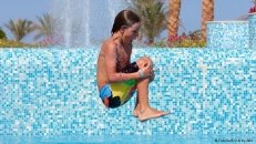 Ein Junge springt mit angezogenen Knien ins Wasser