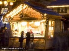 Eine beleuchtete Bude auf einem Weihnachtsmarkt mit einem Paar davor