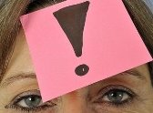Ein Zettel mit einem Ausrufezeichen auf einer Stirn