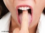 Eine Frau steckt sich einen Finger in den Mund, um sich zu übergeben