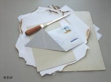 Mehrere Blätter Papier, ein Brieföffner und Blätter, die am Rande angezündet wurden