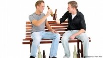 Zwei Männer sitzen auf einer Bank und trinken Alkohol