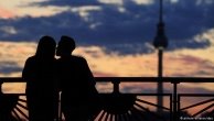 Bild von einem küssenden Paar in der Dämmerung, man sieht die Silhouette vor der Skyline von Berlin 