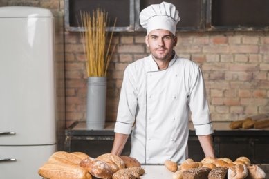 Portrait of handsome baker at the bakery with breads in bakery ...