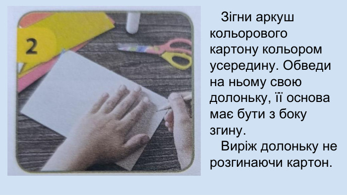  Зігни аркуш кольорового картону кольором усередину. Обведи на ньому свою долоньку, її основа має бути з боку згину. Виріж долоньку не розгинаючи картон.
